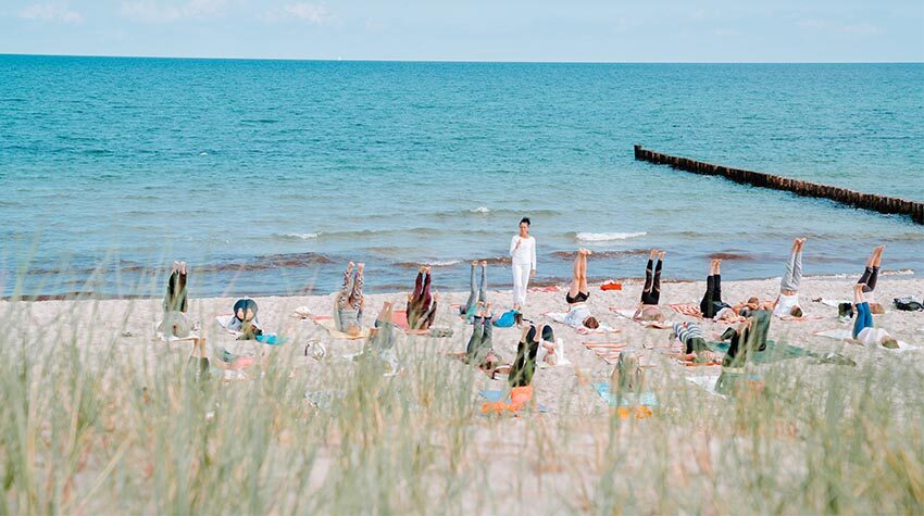 Yoga braucht kein Studio. Ihr könnt es genauso am Strand praktizieren und dabei dem Rauschen der Ostsee zuhören.