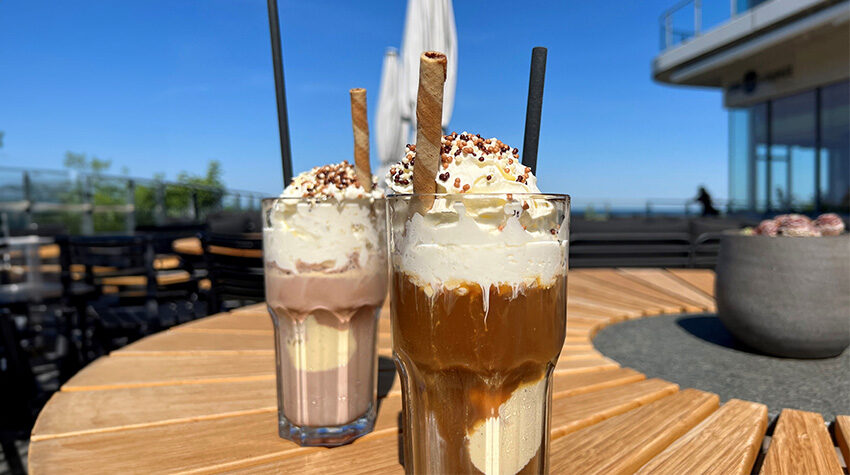 Zwei Gläser mit Eiskaffee, die jeweils Sahne und eine Kugel Vanilleeis beeinhalten.