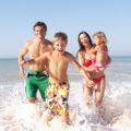 Eine Familie hält ihr Kind an den Händen und spielt am Ostsee Strand © Adobe Stock, Monkey Business