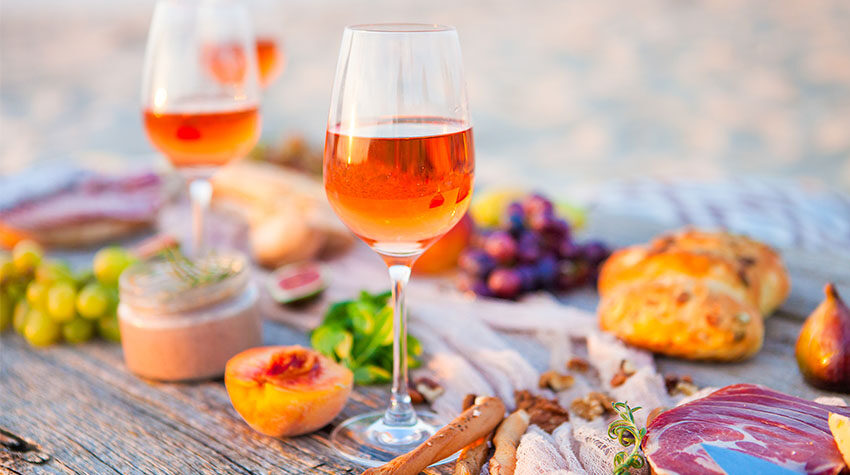 Weingläaser auf Tisch am Strand mit kleinen Speisen und Weintrauben. ©Adobe Stock, yatcenko