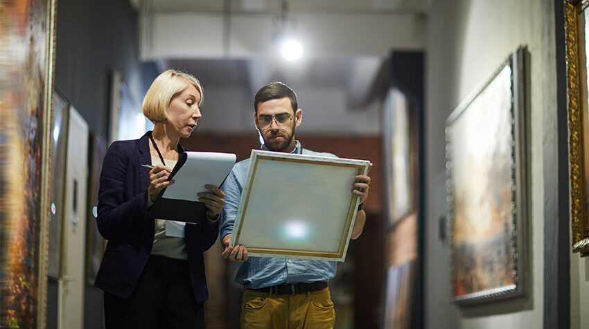 Zwei Personen, die ein Gemälde begutachten und sich Notizen dazu machen. ©Adobe Stock, Seventyfour