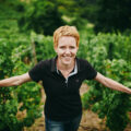 Winzerin Anette Closheim, die in einem Feld voller Weintraubenreben steht und lächelt. ©Anette Closheim