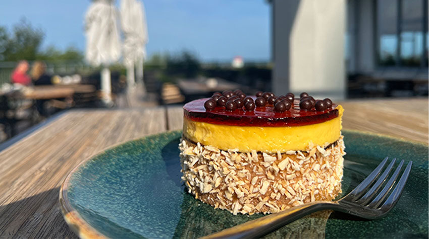 Ein Dessert mit Passionsfrucht und Kokosnuss auf einem grünen Teller, serviert auf der Terrasse des SEASIDE in Ahrenshoop.