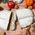 Ein aufgeschnittener Stollen liegt auf einem weihnachtlich dekorierten Tisch.