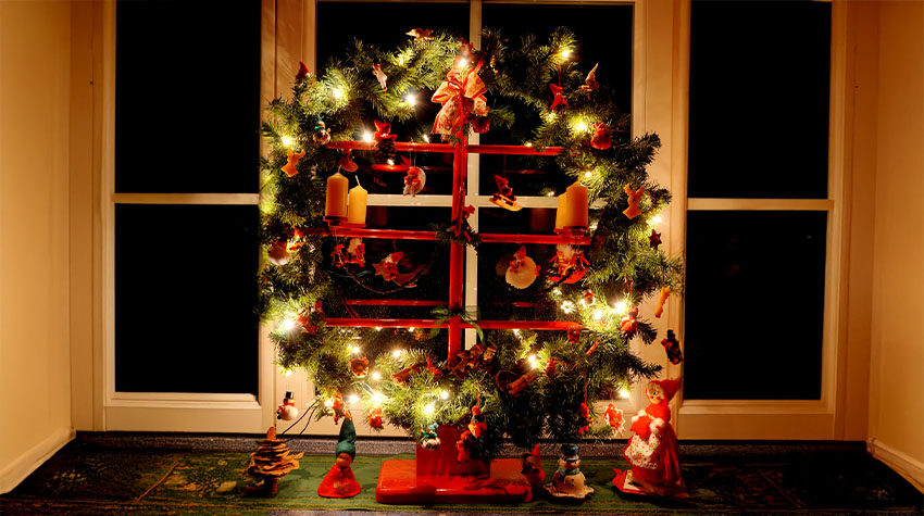 Traditionell geschmückter Jöölboom auf einer Fensterbank, beleuchtet.