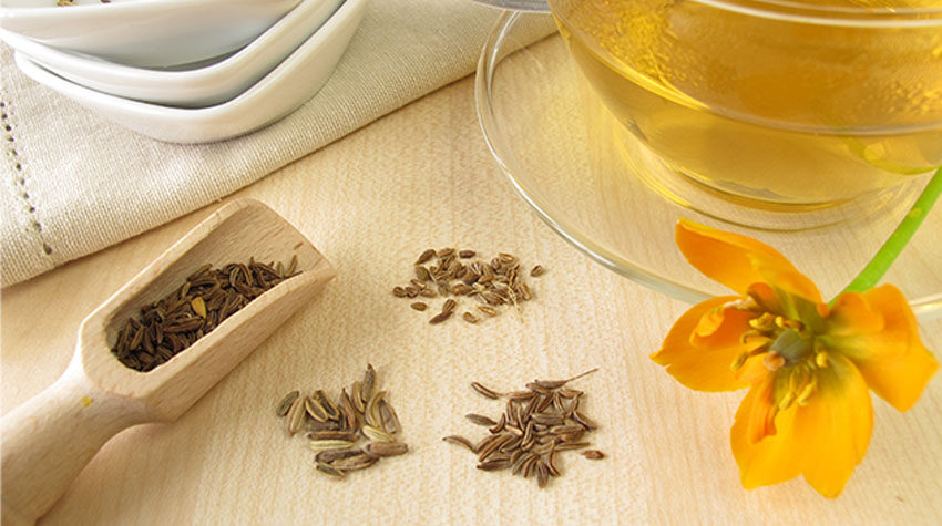 Anissamen neben einer Tasse frisch aufgebrühtem Tee und einer gelben Blüte.