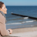 Frau geniesst frische Seeluft und Sonnenlicht an der Ostsee.